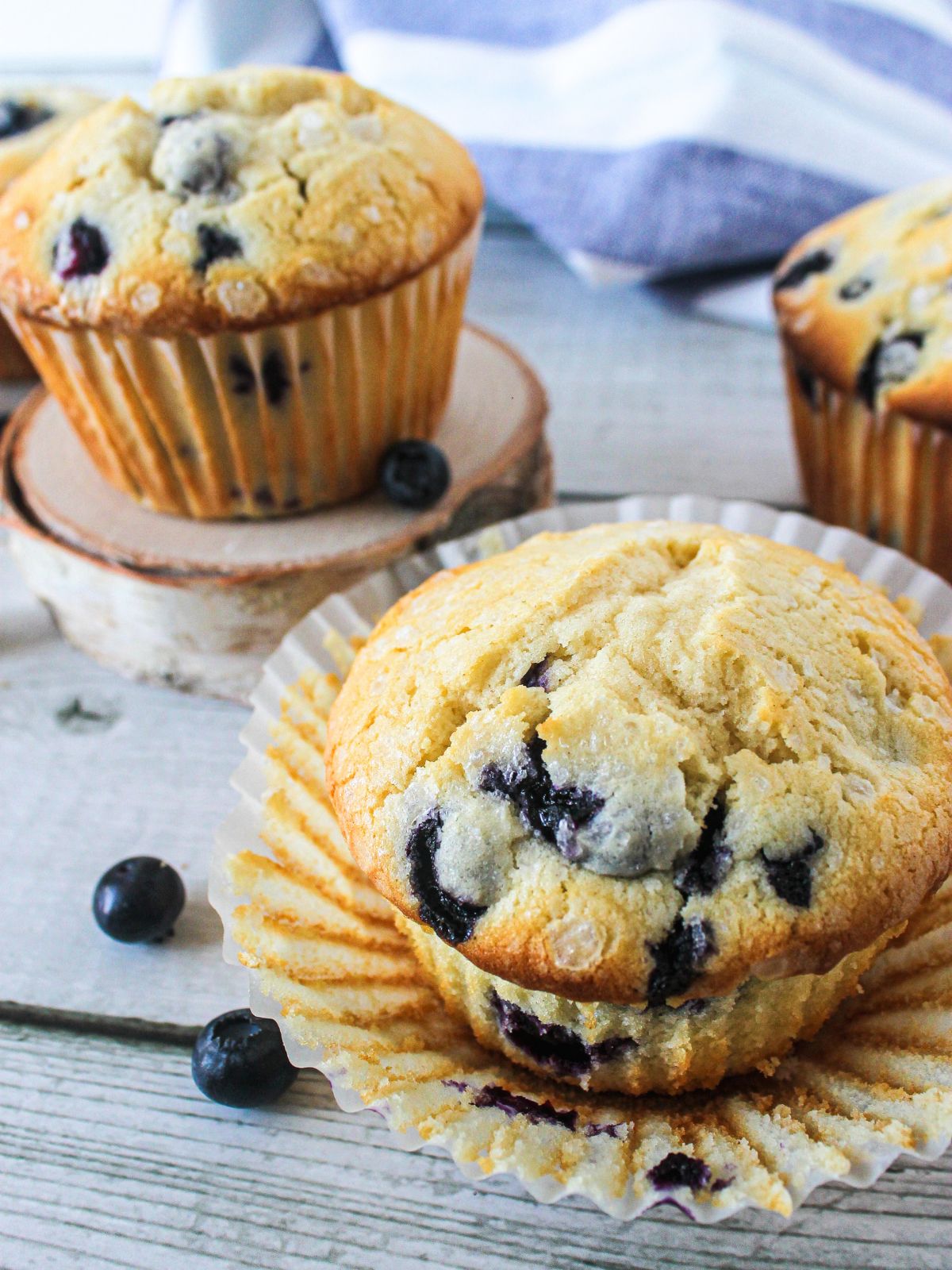 classic homemade blueberry muffins on cutting board with scattered berries around.